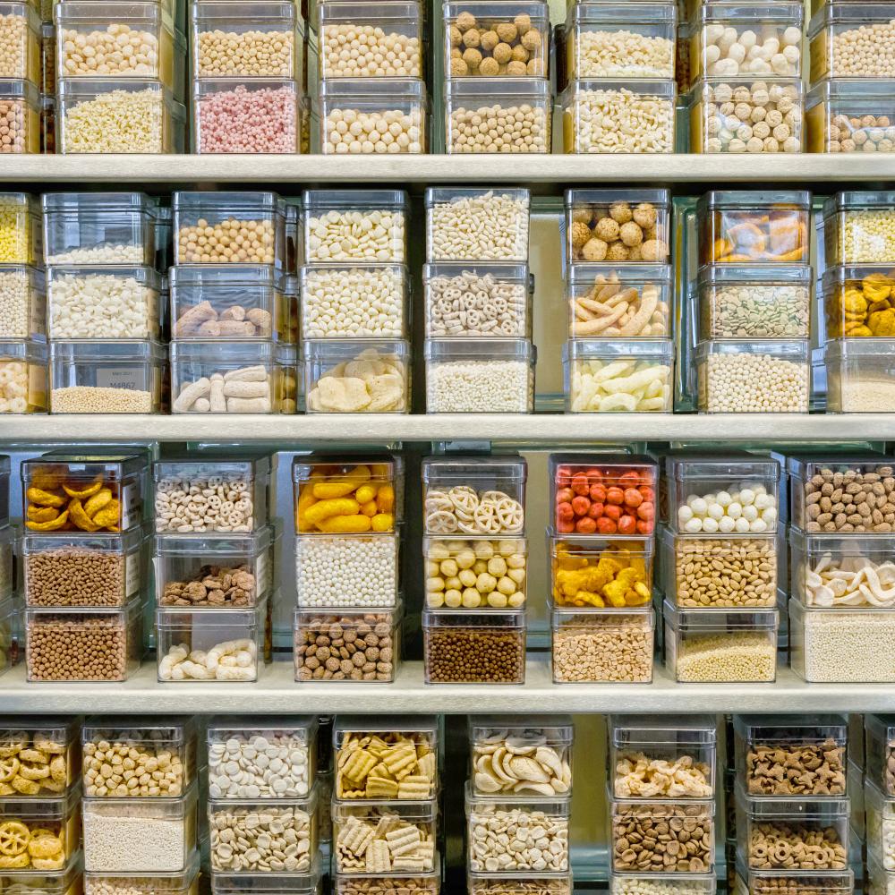 Verschiedenste Cerealien aus der eigenen Produktion in durchsichtigen Dosen im Regal.
