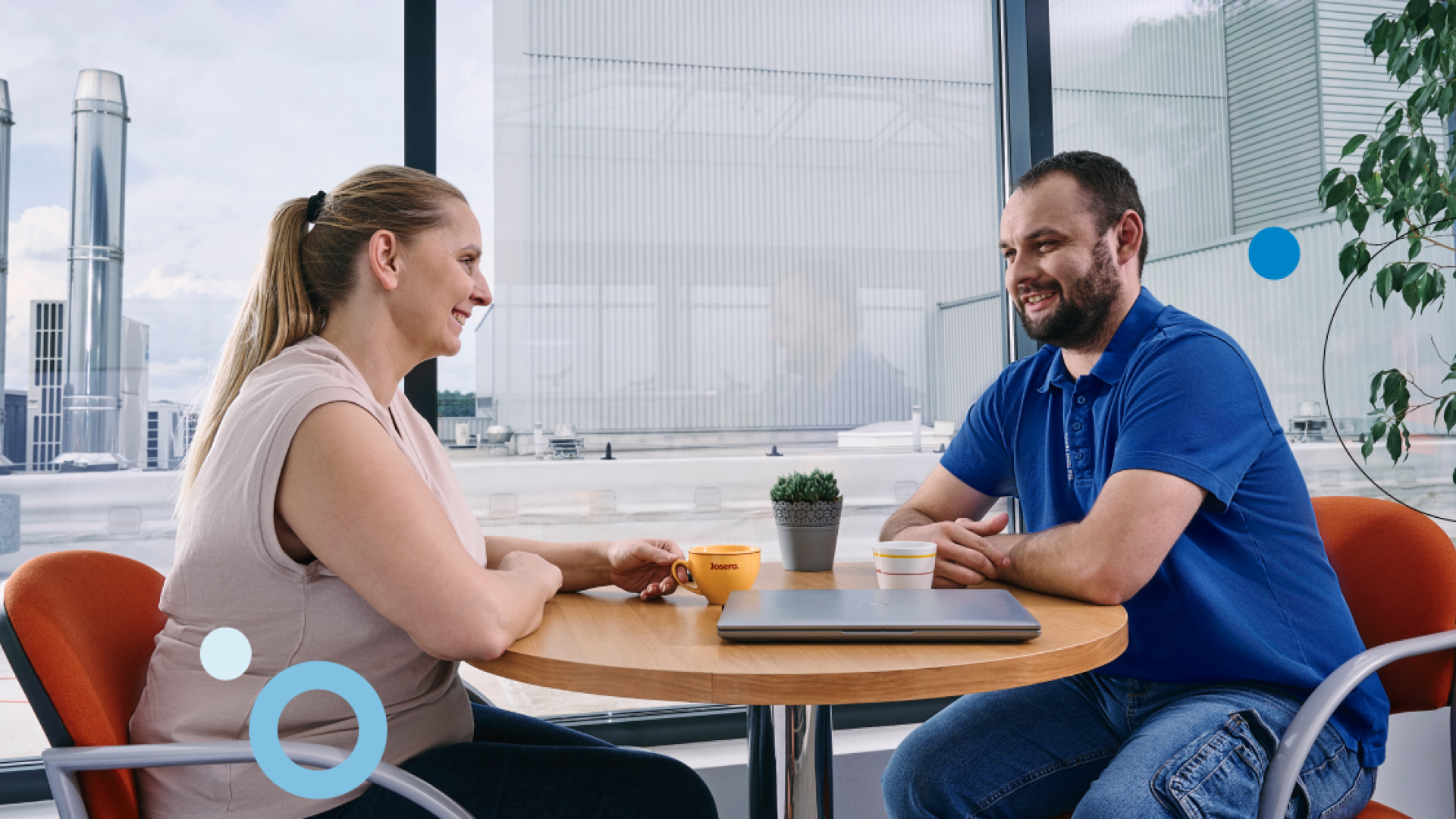 Two people sitting on a table. In the background you can see the company.